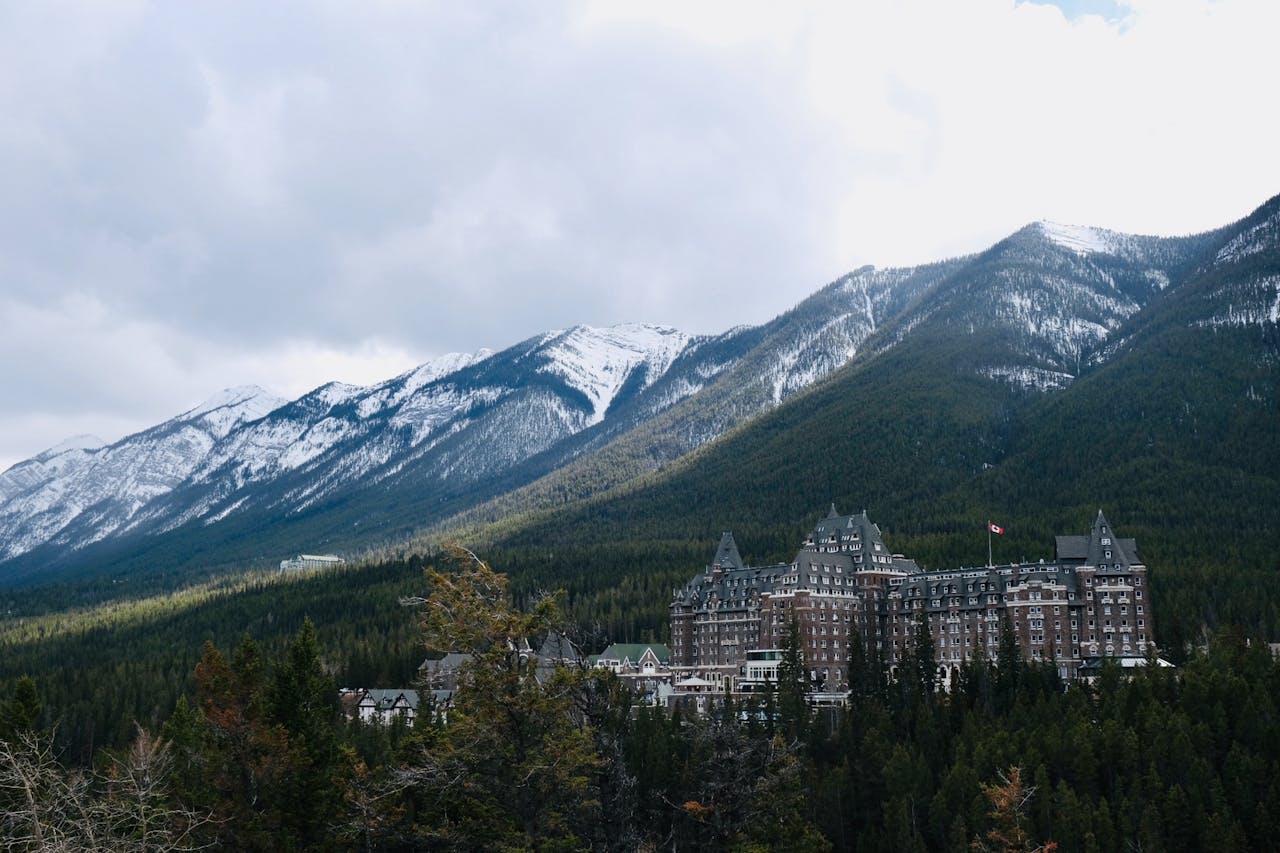 Scenic view of Banff Springs Hotel amidst snow-capped mountains and greenery.
